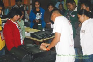 DESPERATELY SEEKING FOR A SOLUTION. The Board of Election Inspectors of Clustered Precint 104 and the Smartmatic technician try to solve the mystery of a Precinct Count Optical Scanner (PCOS) that worked perfectly until it was about count the votes.Would the BEI continued trying if they had known that there was a possibility that the voters would be disenfranchised if the votes would not be counted by the PCOS? Photo by Noel Godinez
